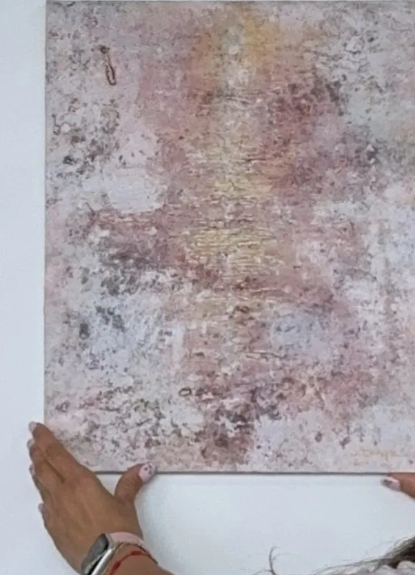 Obra abstracta vertical en rosa empolvado con textura, sostenida por la artista